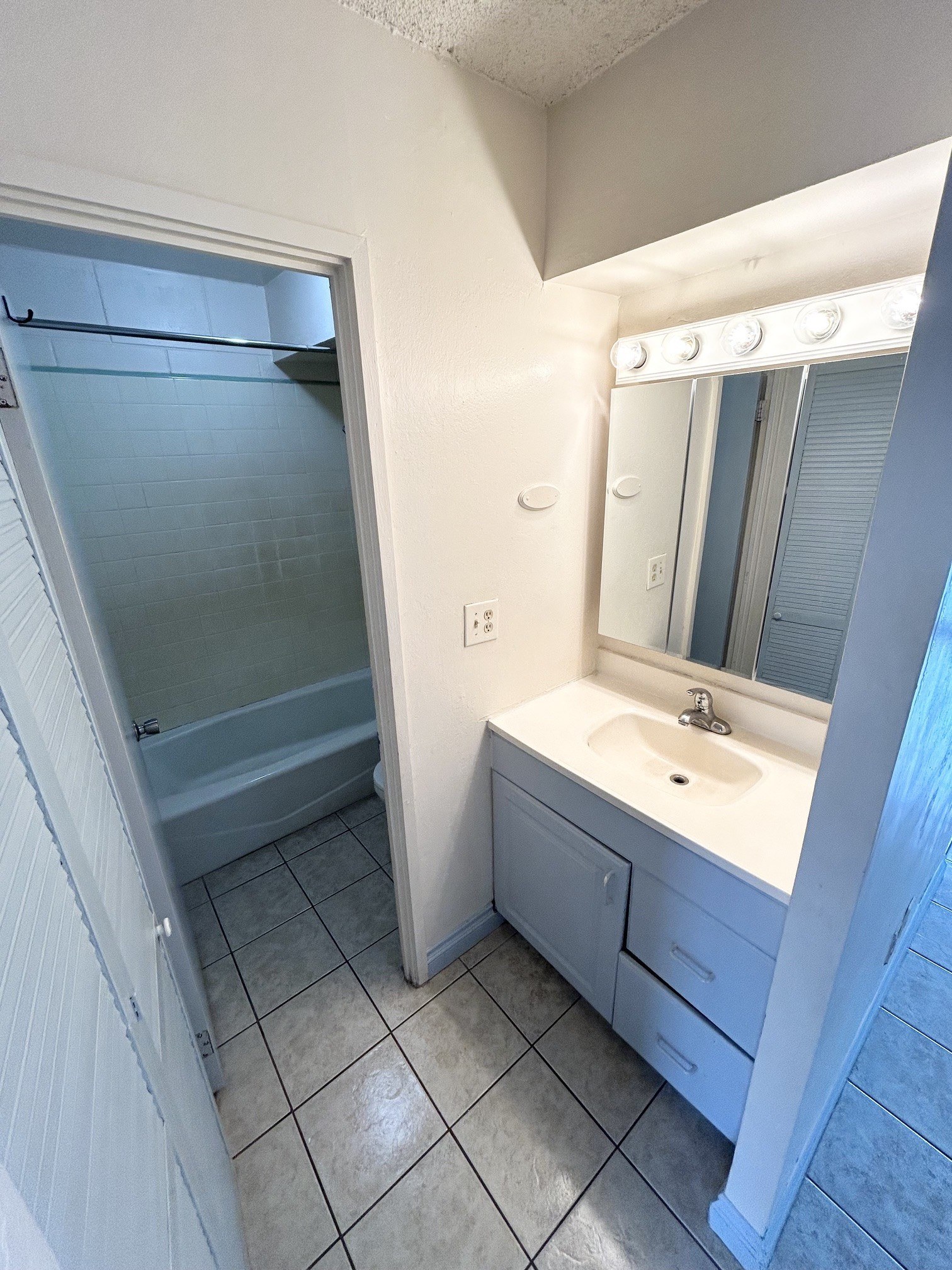 A white bathroom with a sink, mirror, and shower.